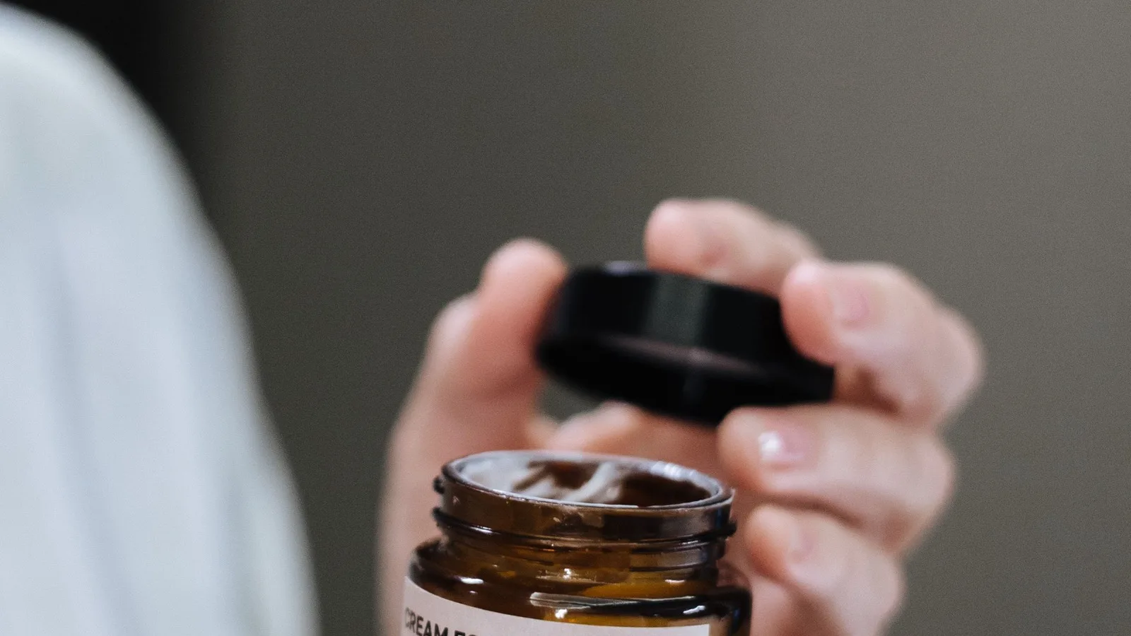 A jar of face cream held in hands for product comparison.