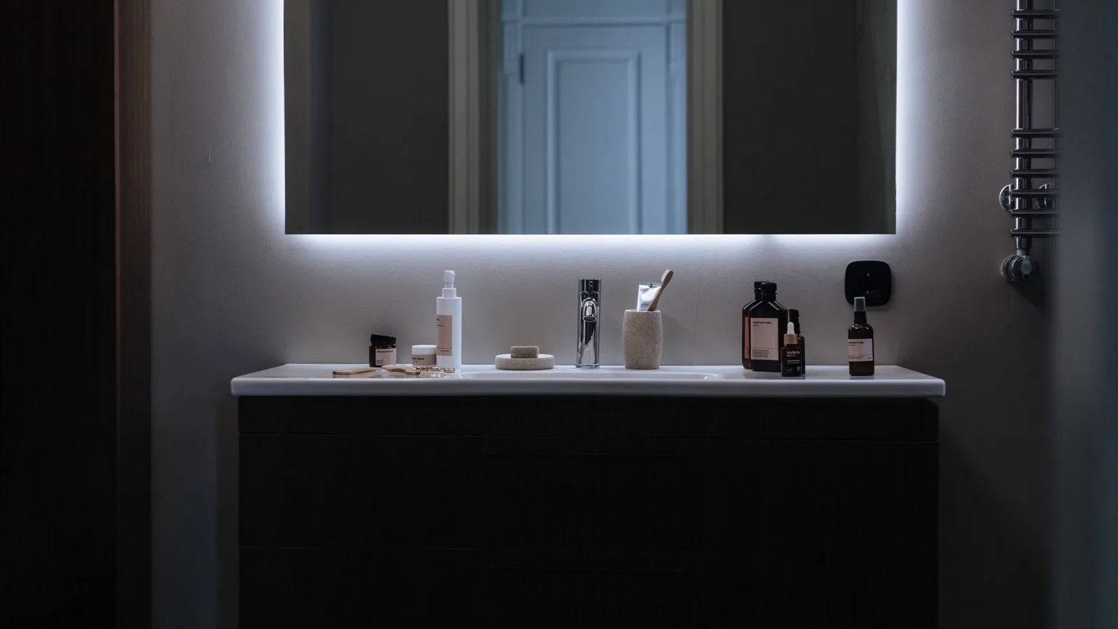 Organized bathroom vanity with skincare products near a mirror.