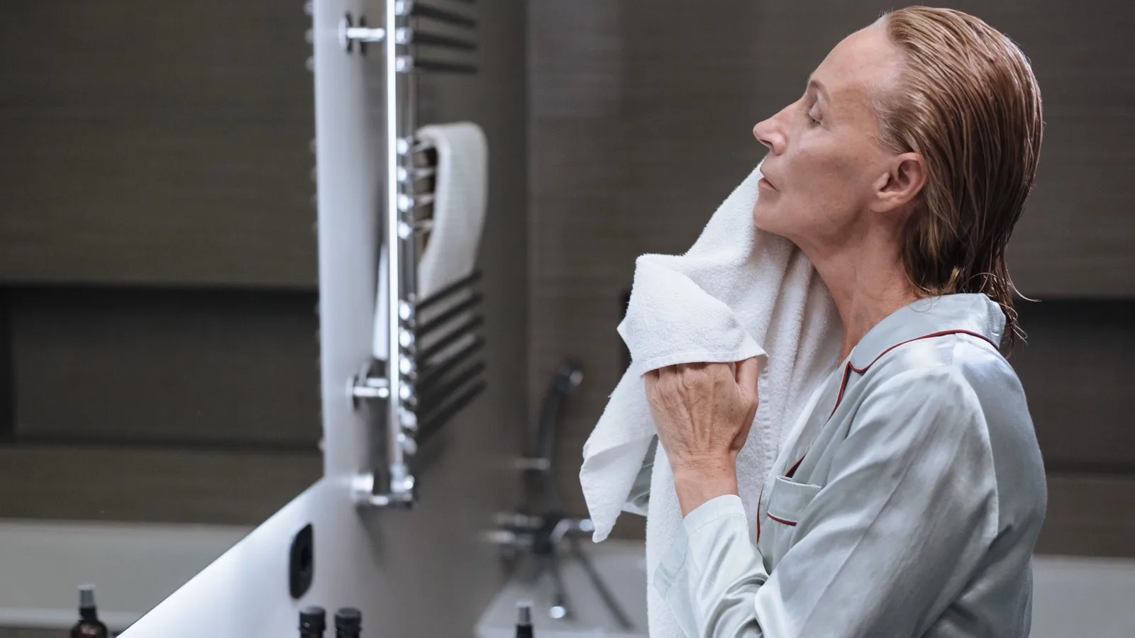 A senior woman drying her face during a bathroom skincare routine.