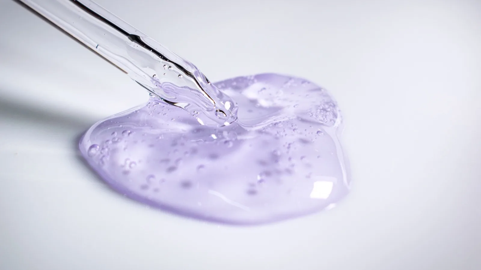 A pipette dispensing a drop of skincare gel.