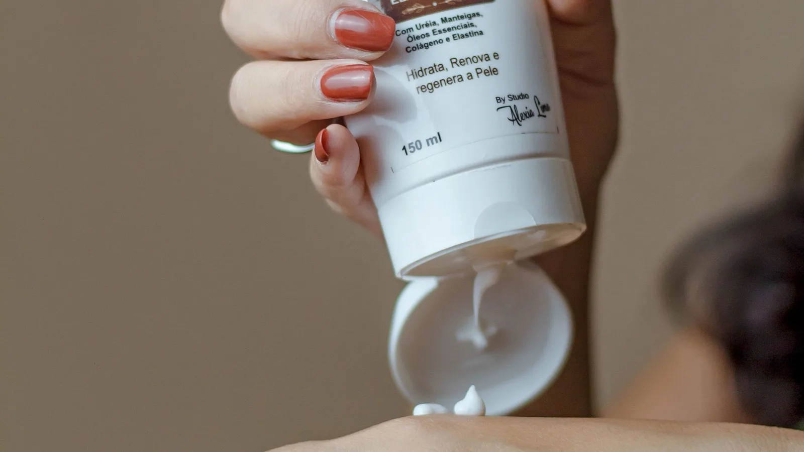 A person applying moisturizer from a tube onto their hand.