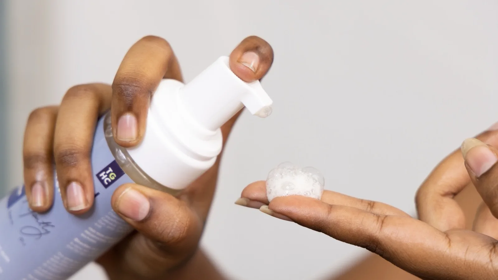 Hands dispensing a gentle facial cleanser for a skincare routine.