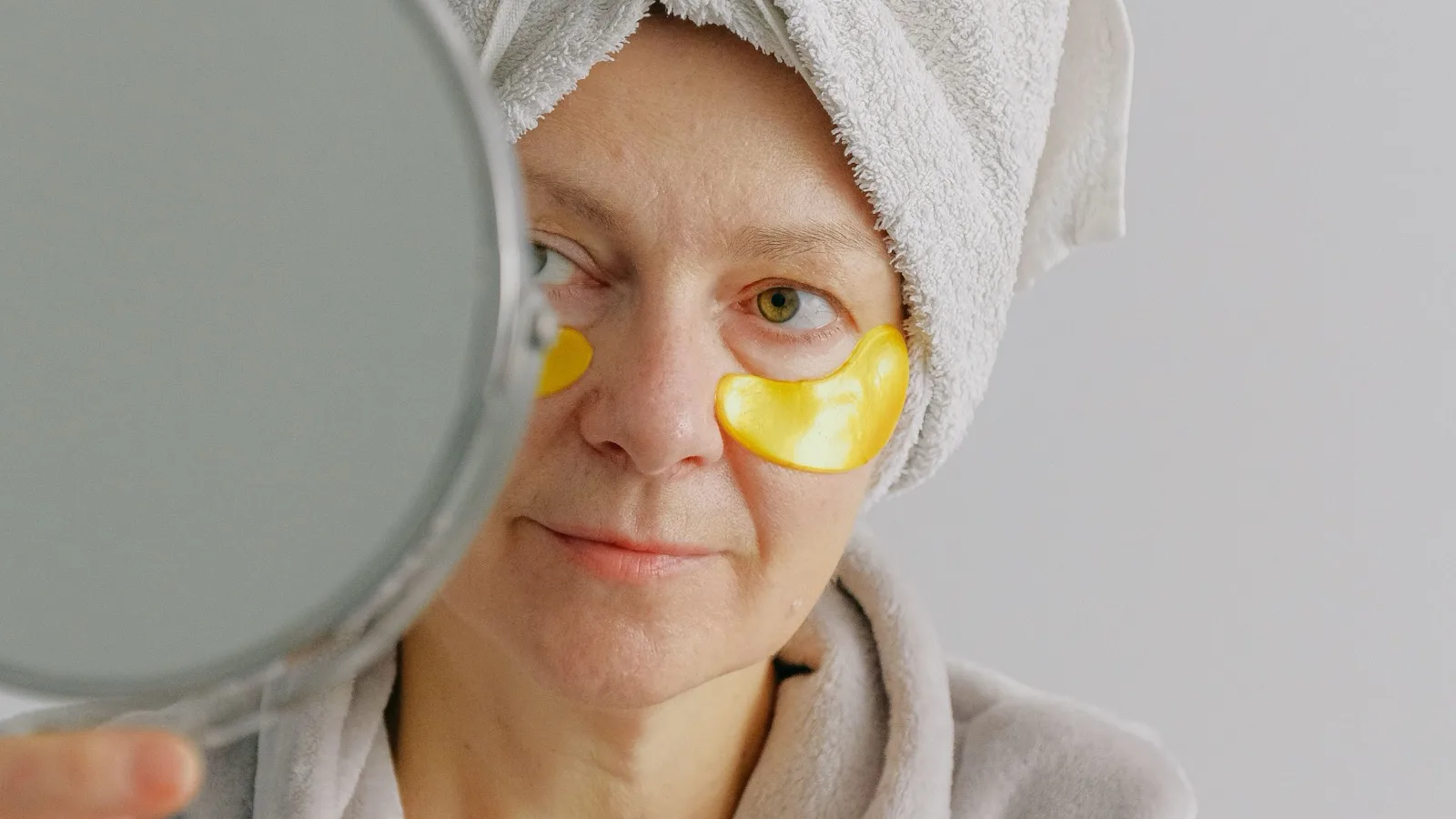 A woman checking her skincare routine in a mirror.