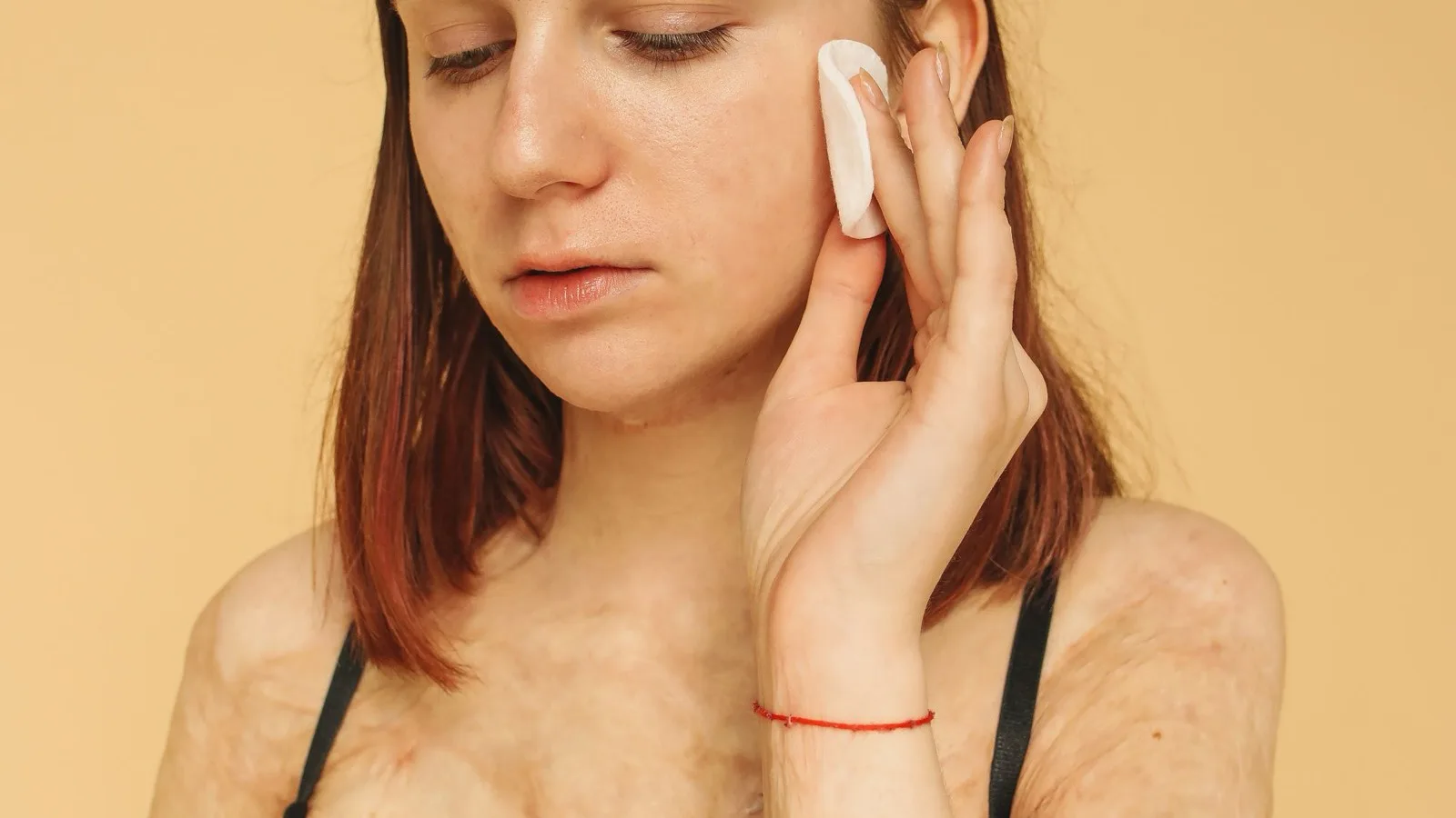 A woman gently using a cotton pad during a skincare routine.