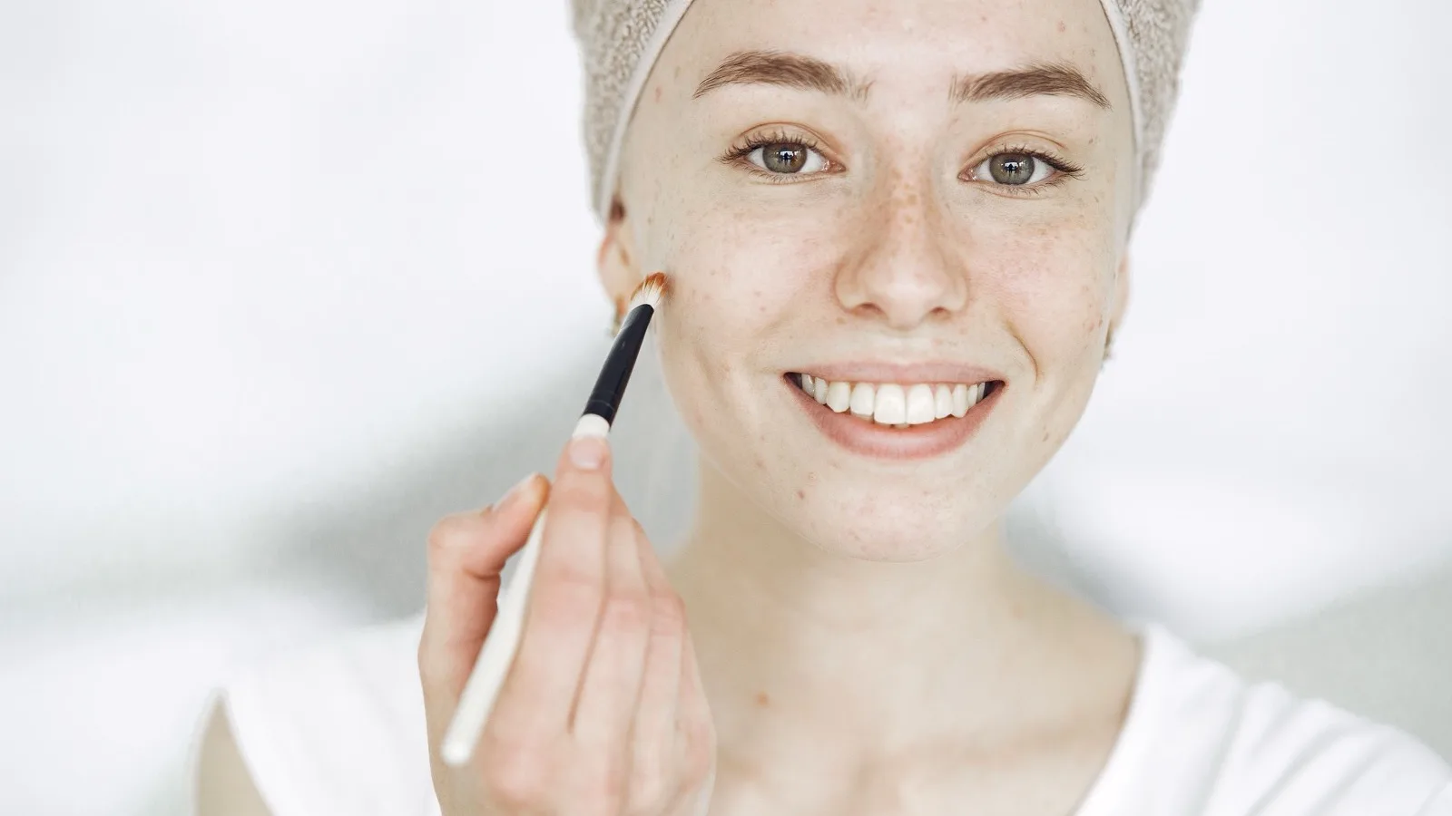 A woman applying a cosmetic product while considering skincare choices.