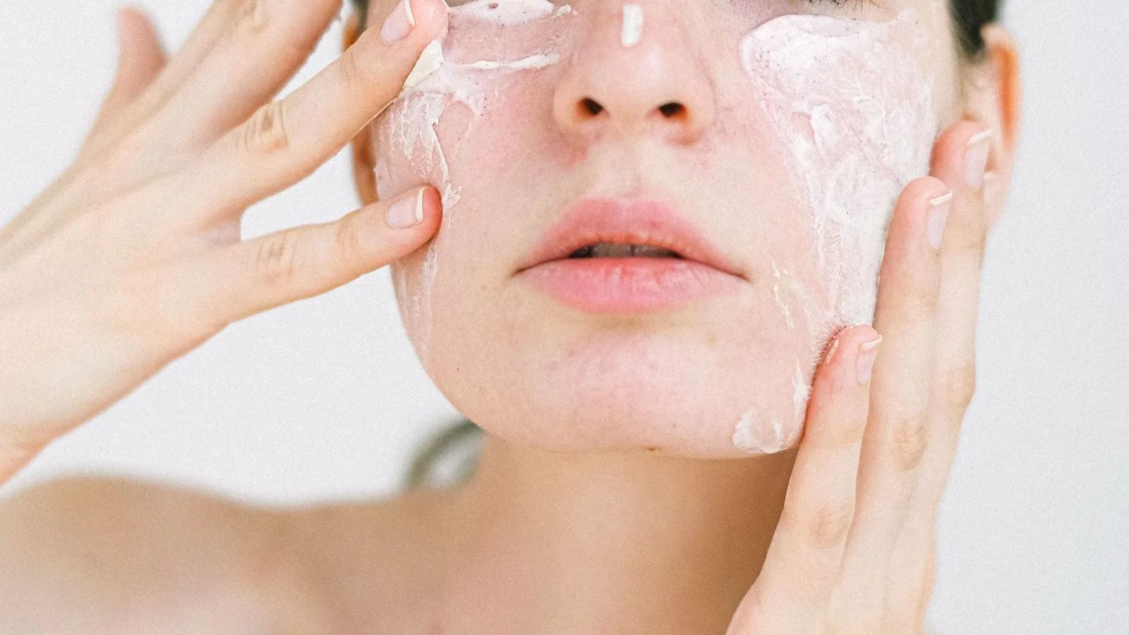 A woman applying moisturizer as part of a simple skincare routine.