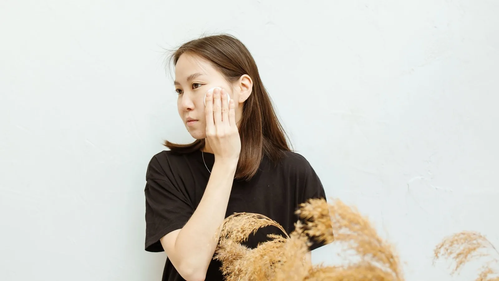 A person using a cotton pad as part of a gentle cleansing routine.