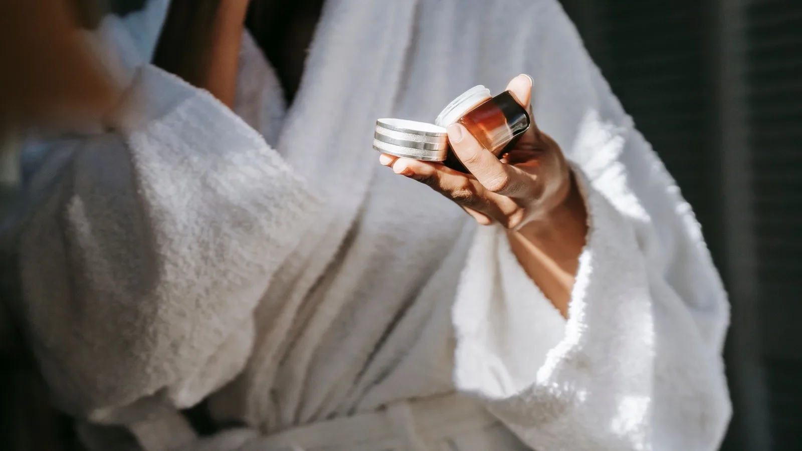 A person applying moisturizer gently while looking in a mirror.