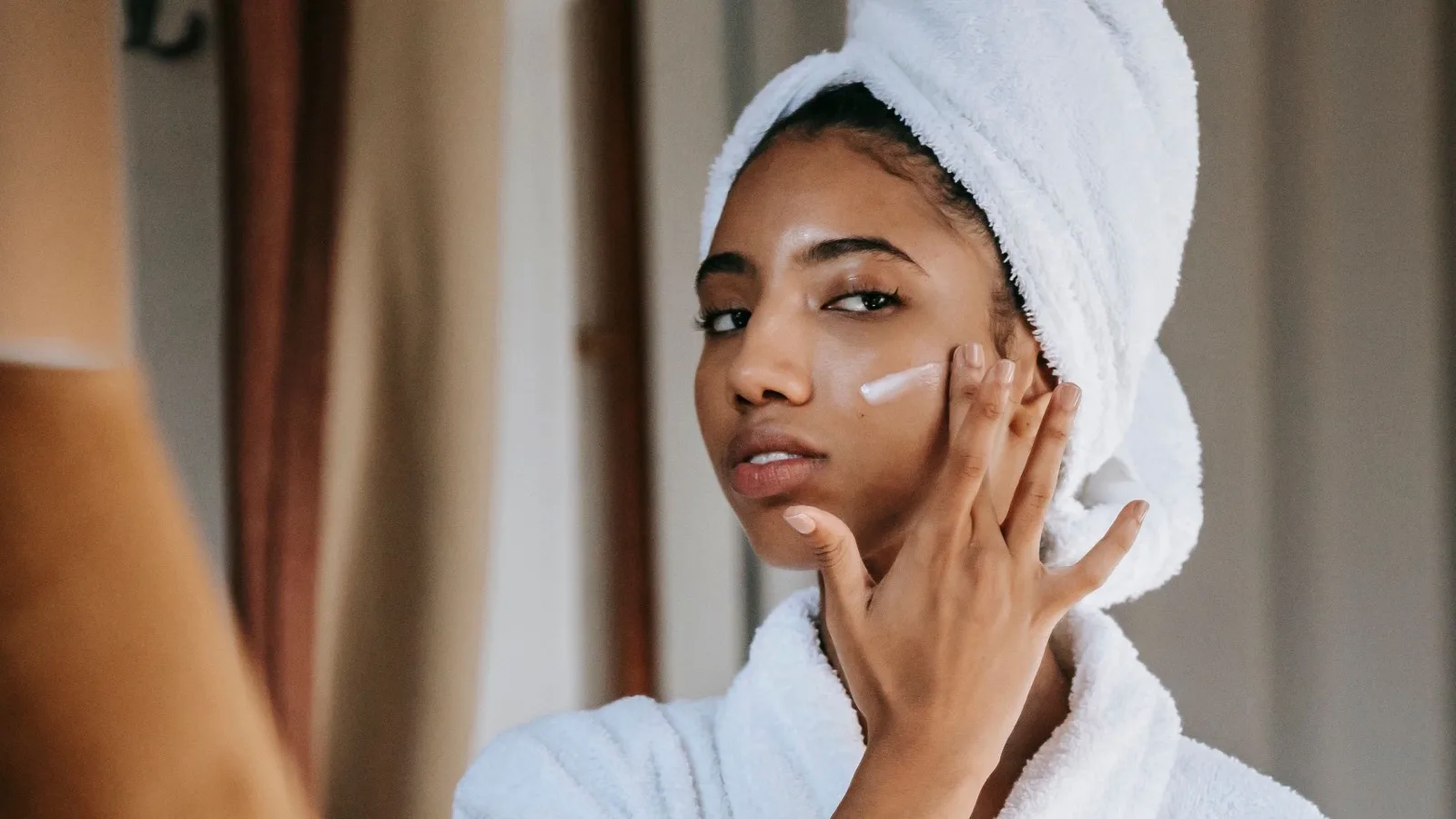 A woman applying moisturizer as part of a calm skincare routine.