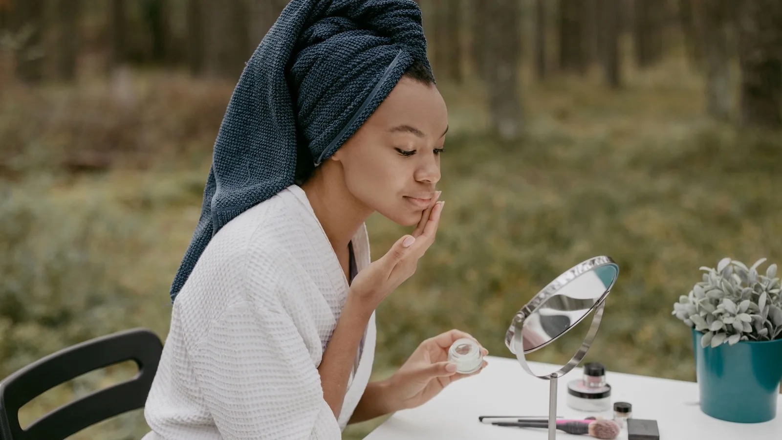 A woman applying face cream during a consistent skincare routine.