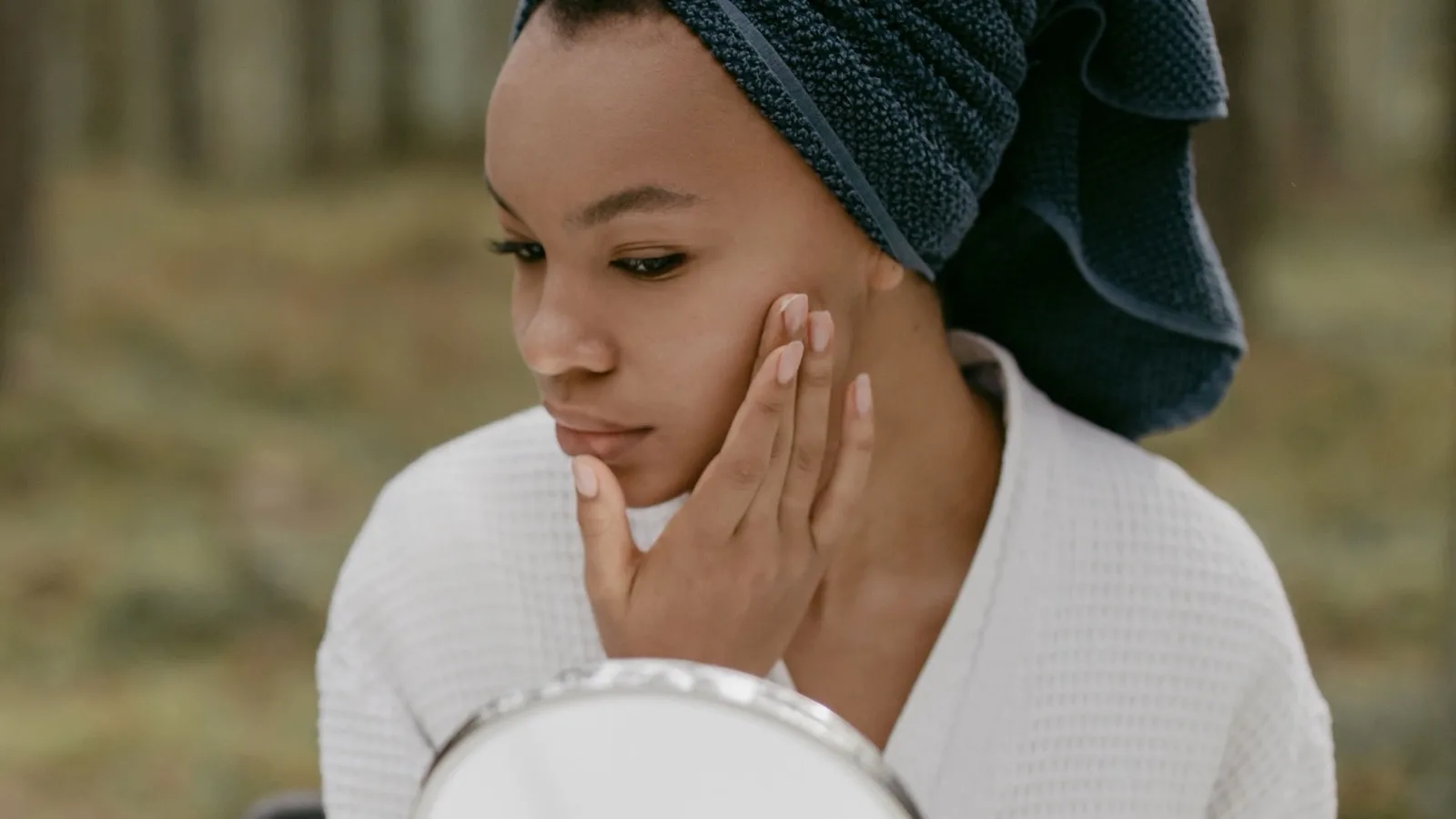 A woman touching her face while following a simple skincare routine.