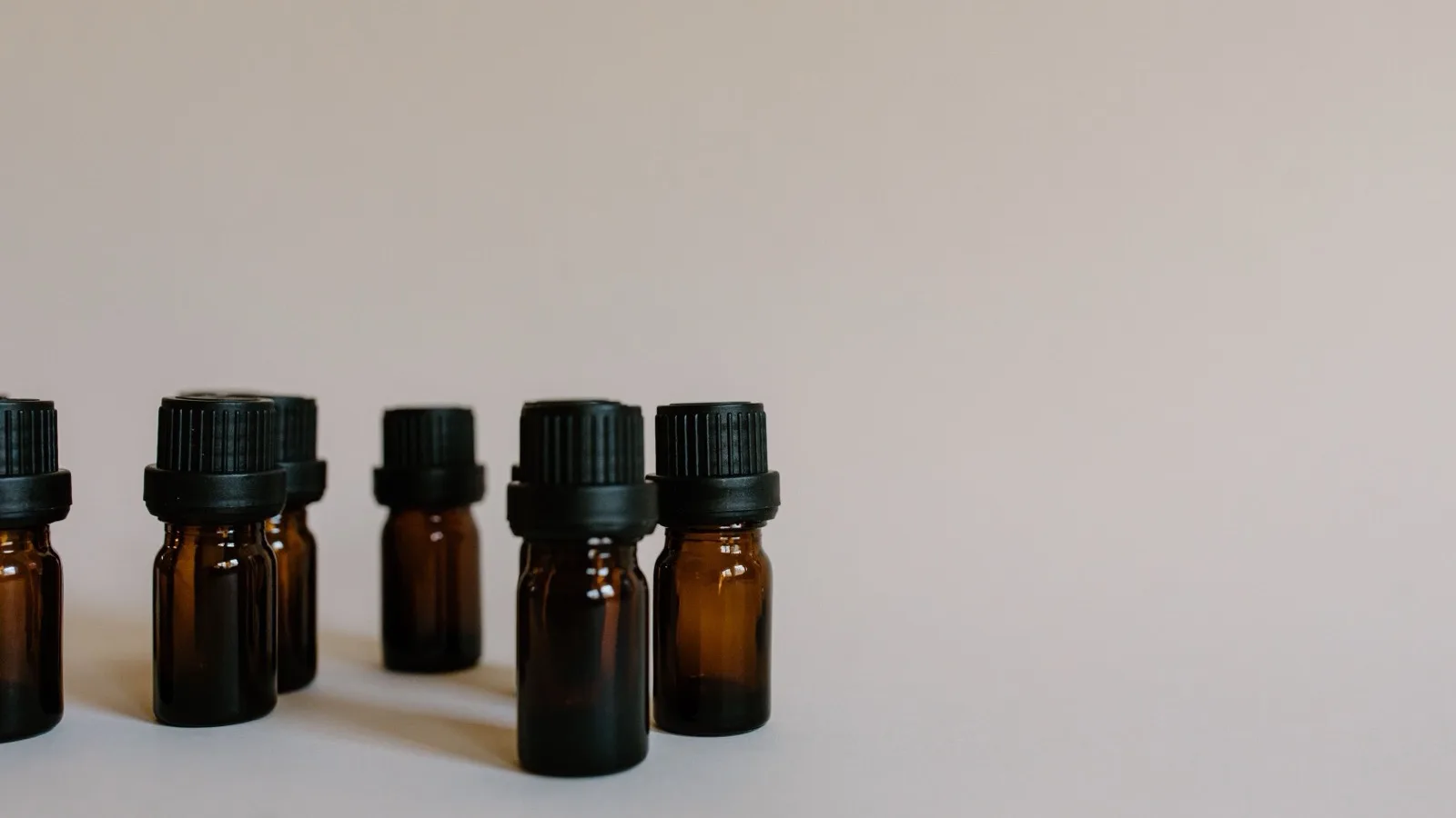 Unlabeled brown skincare bottles arranged on a light surface.
