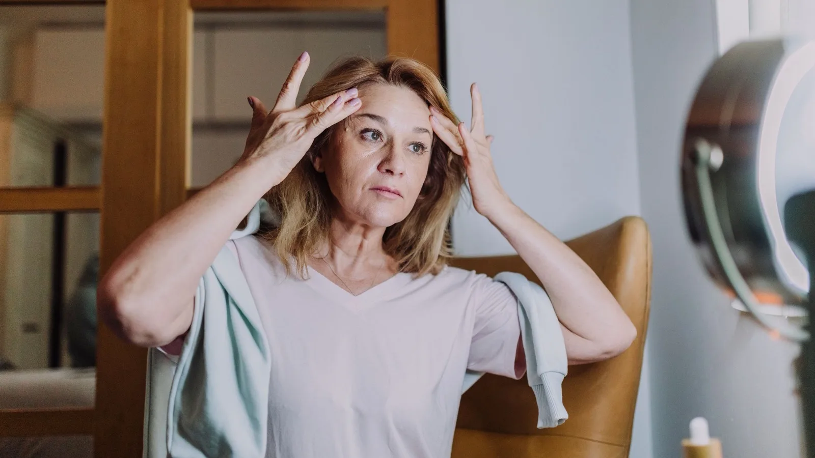A mature woman practicing a gentle skincare routine.