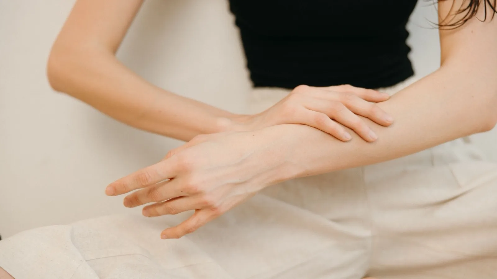 A person applying a small amount of skincare product to an arm.
