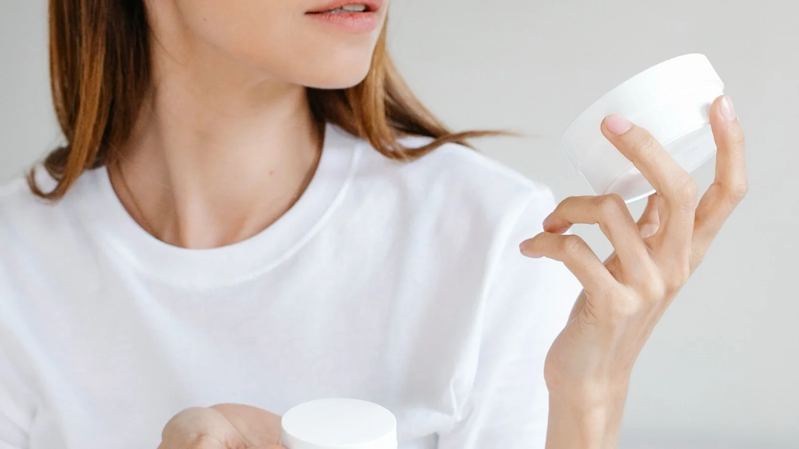 A woman considering skincare choices while testing a product.