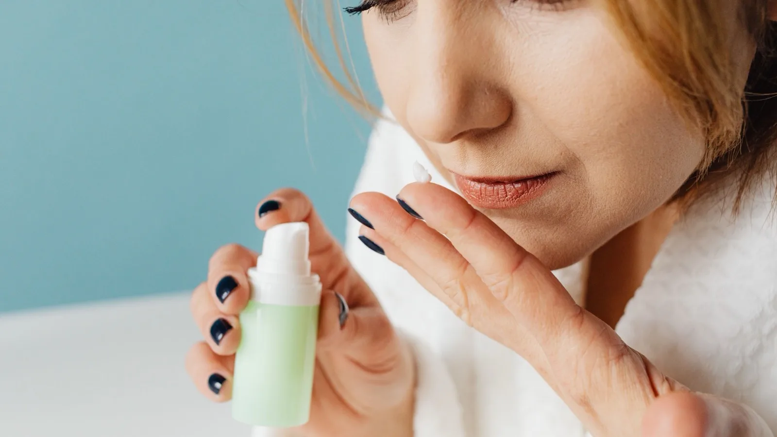 A woman considering a skincare cream in a calm self-care routine.