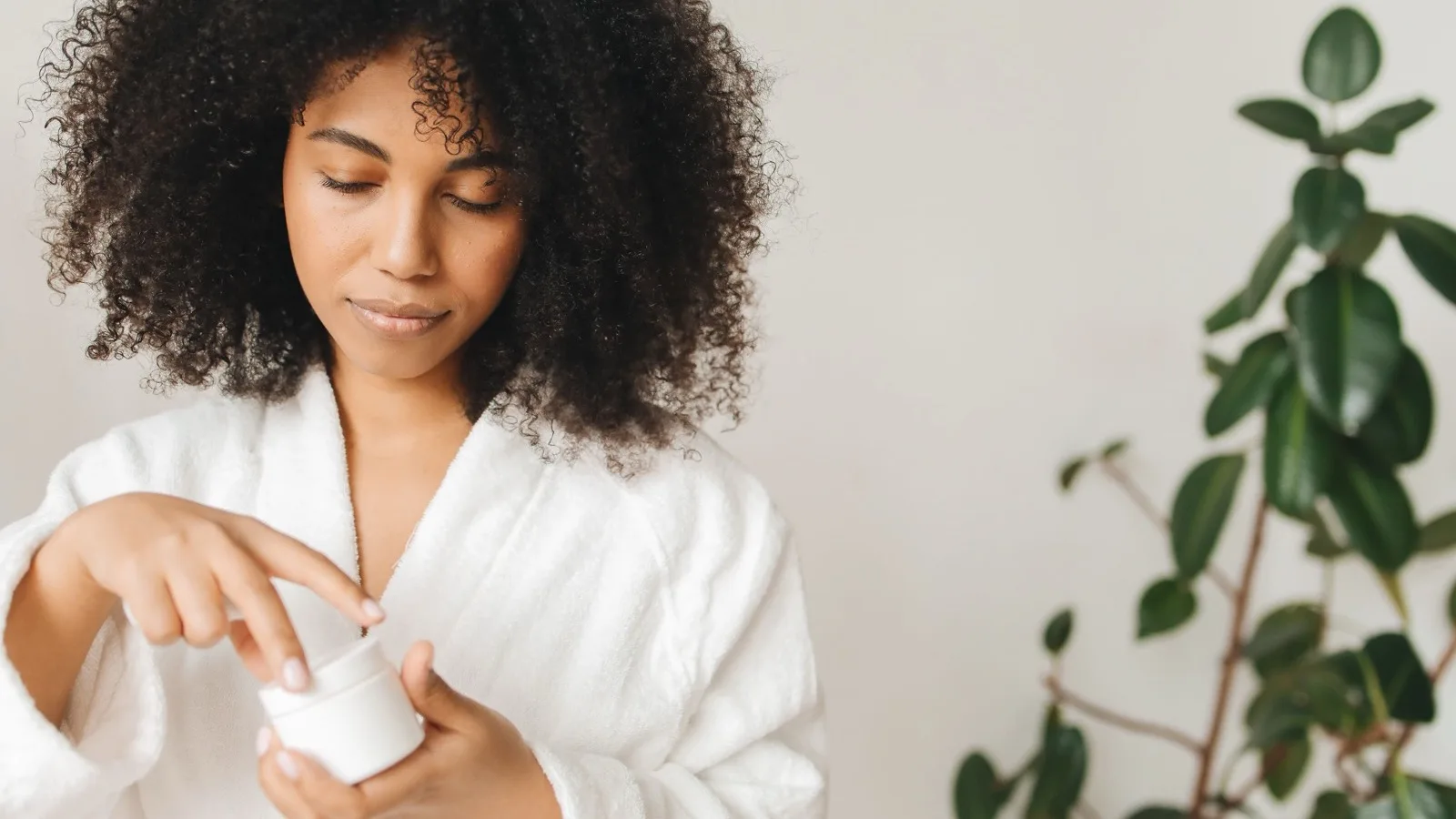 A woman applying skincare in a calm indoor routine.