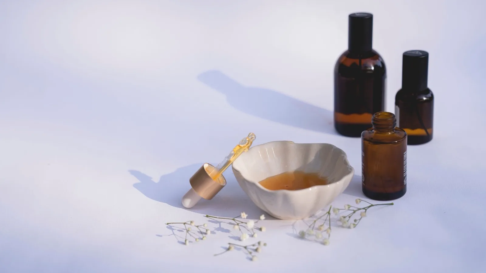 Minimal skincare bottles and a dropper arranged on a neutral surface.