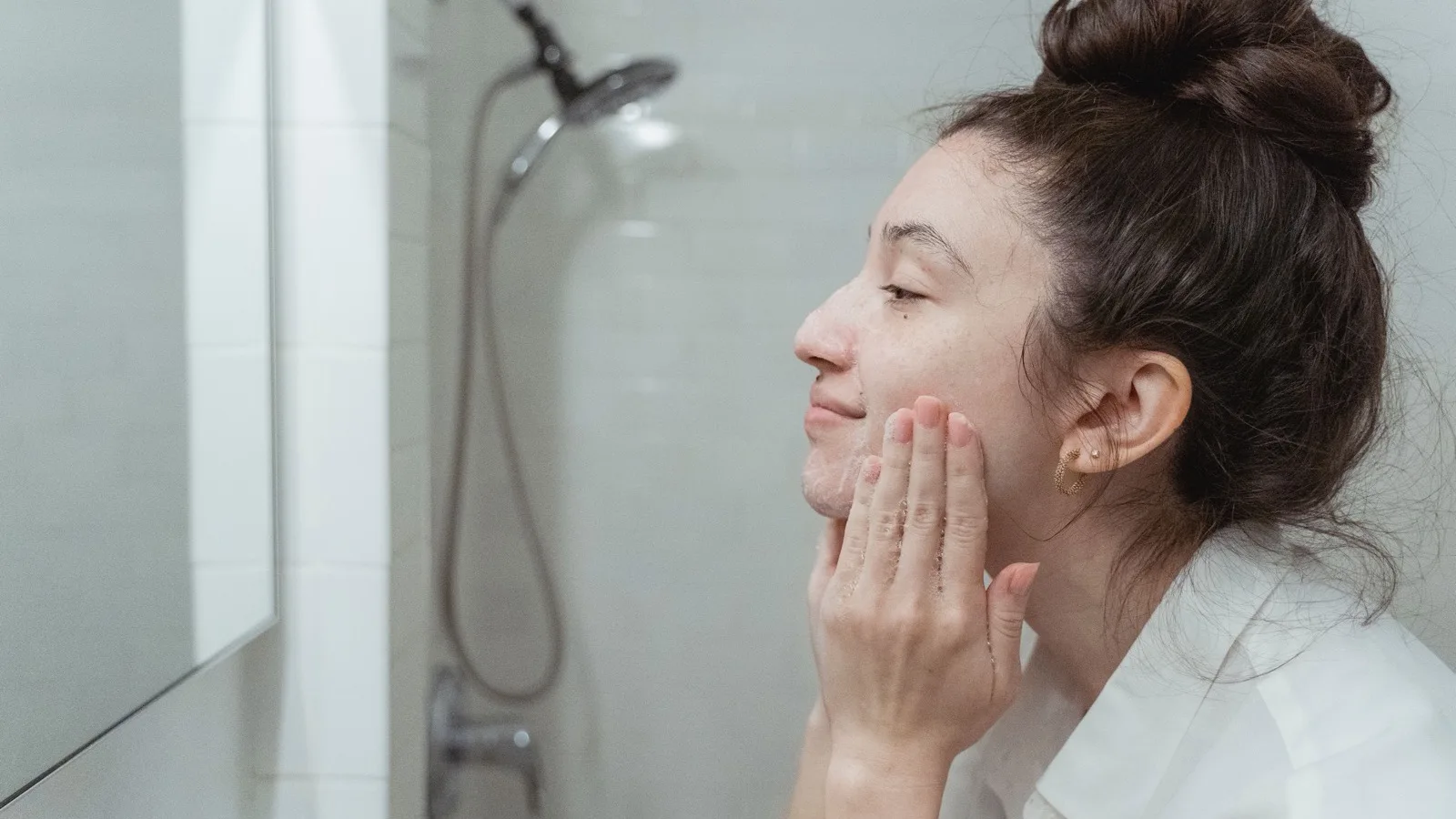 A woman applying facial cream as part of a gentle skincare routine.