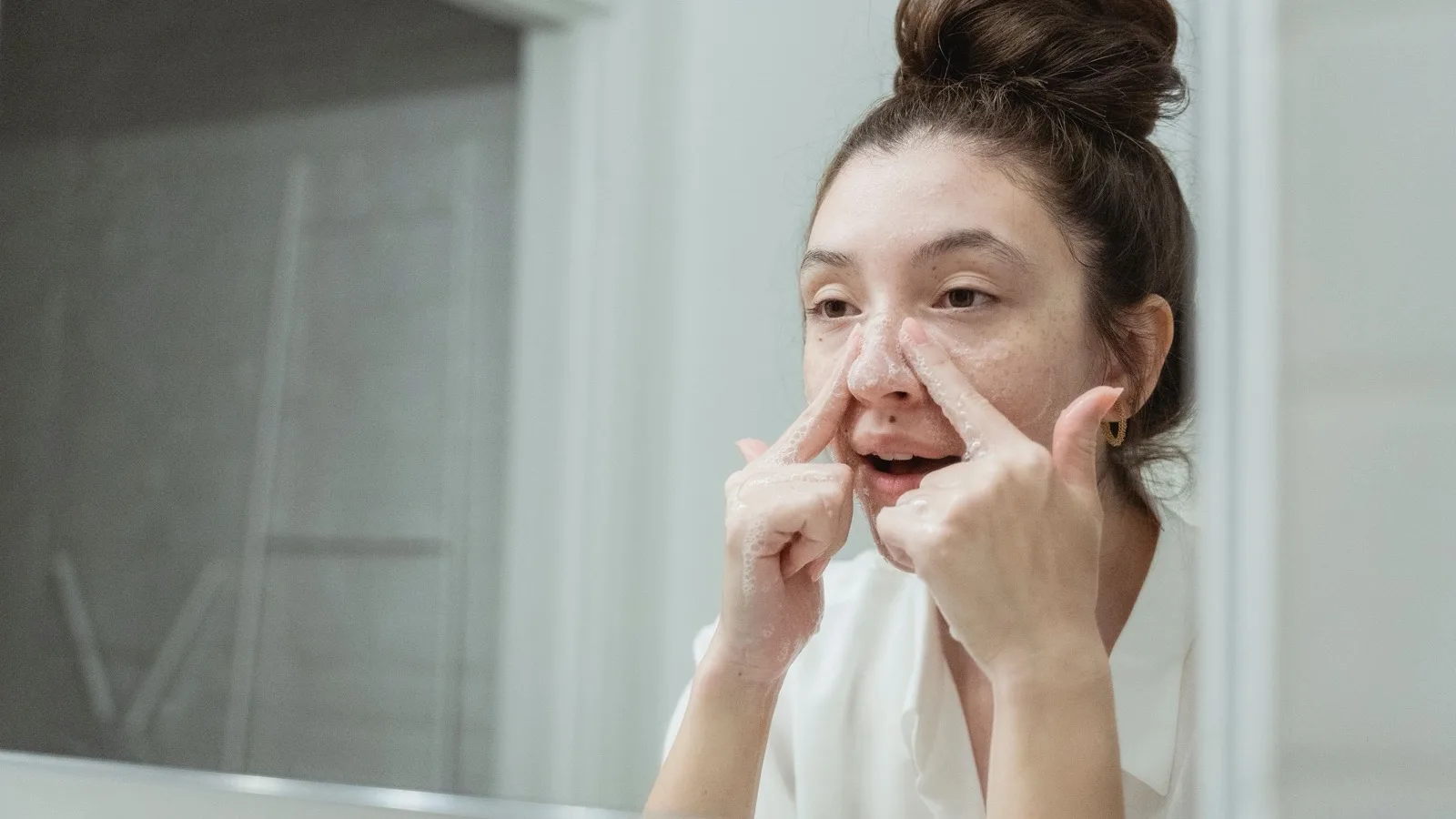A woman washing her face gently in a bathroom.