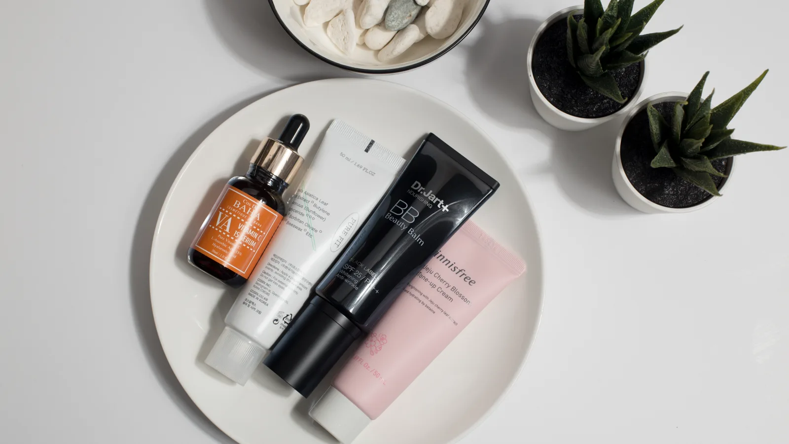 Minimal skincare products arranged on a white plate.