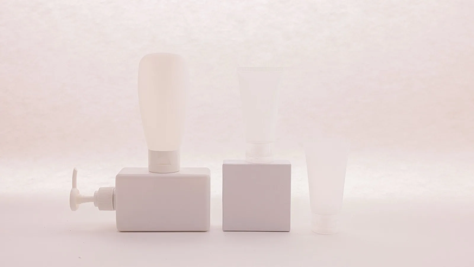 Unlabeled white cosmetic containers arranged for comparing product formulas.