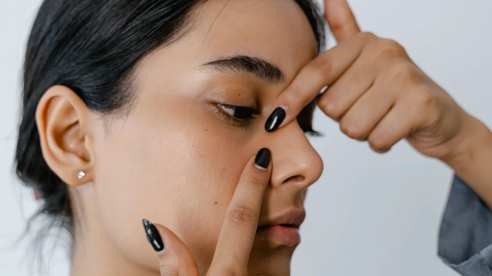 A woman performing a gentle facial massage as part of self-care.