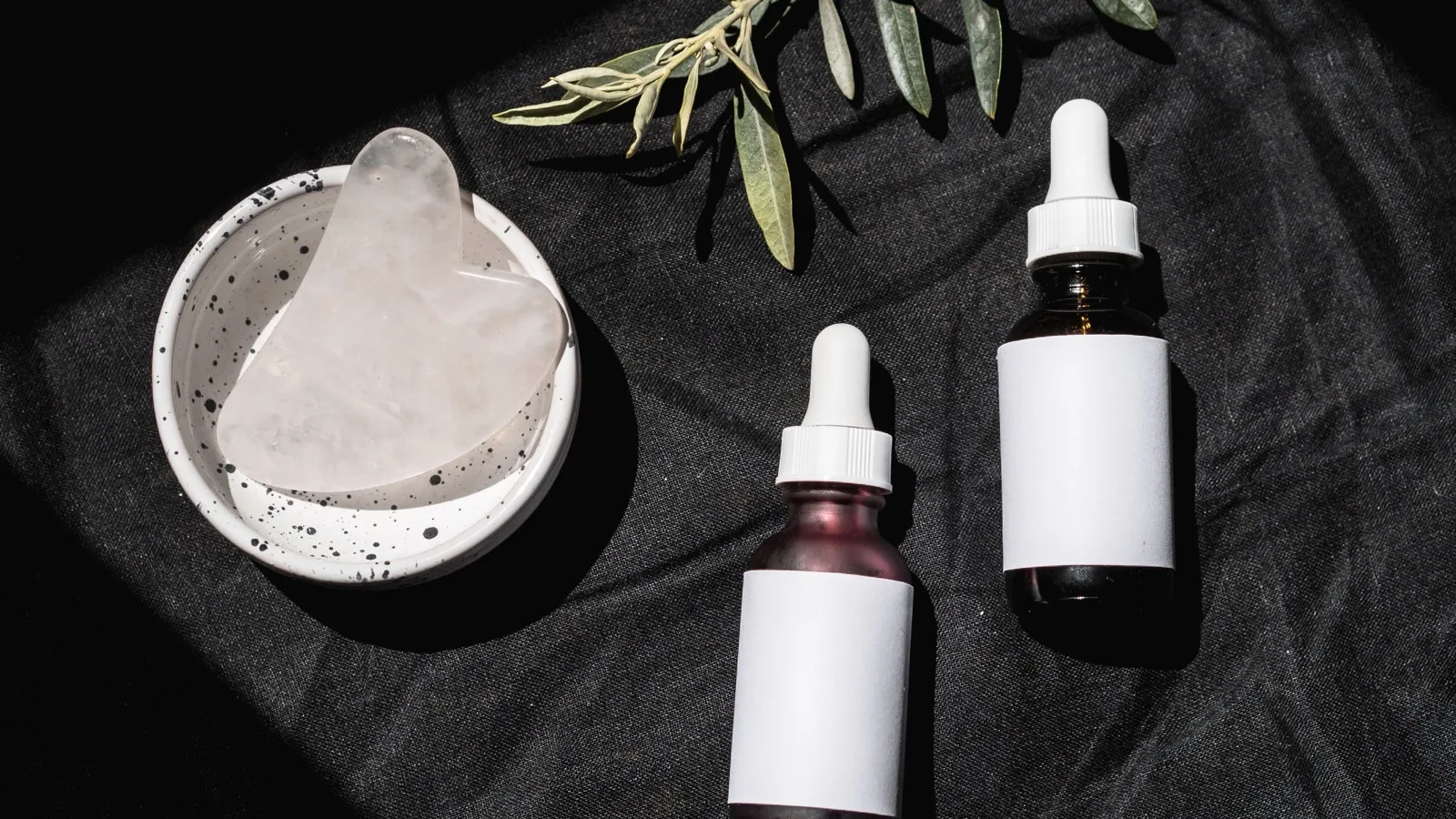 Skincare bottles and a gua sha tool arranged for ingredient comparison.