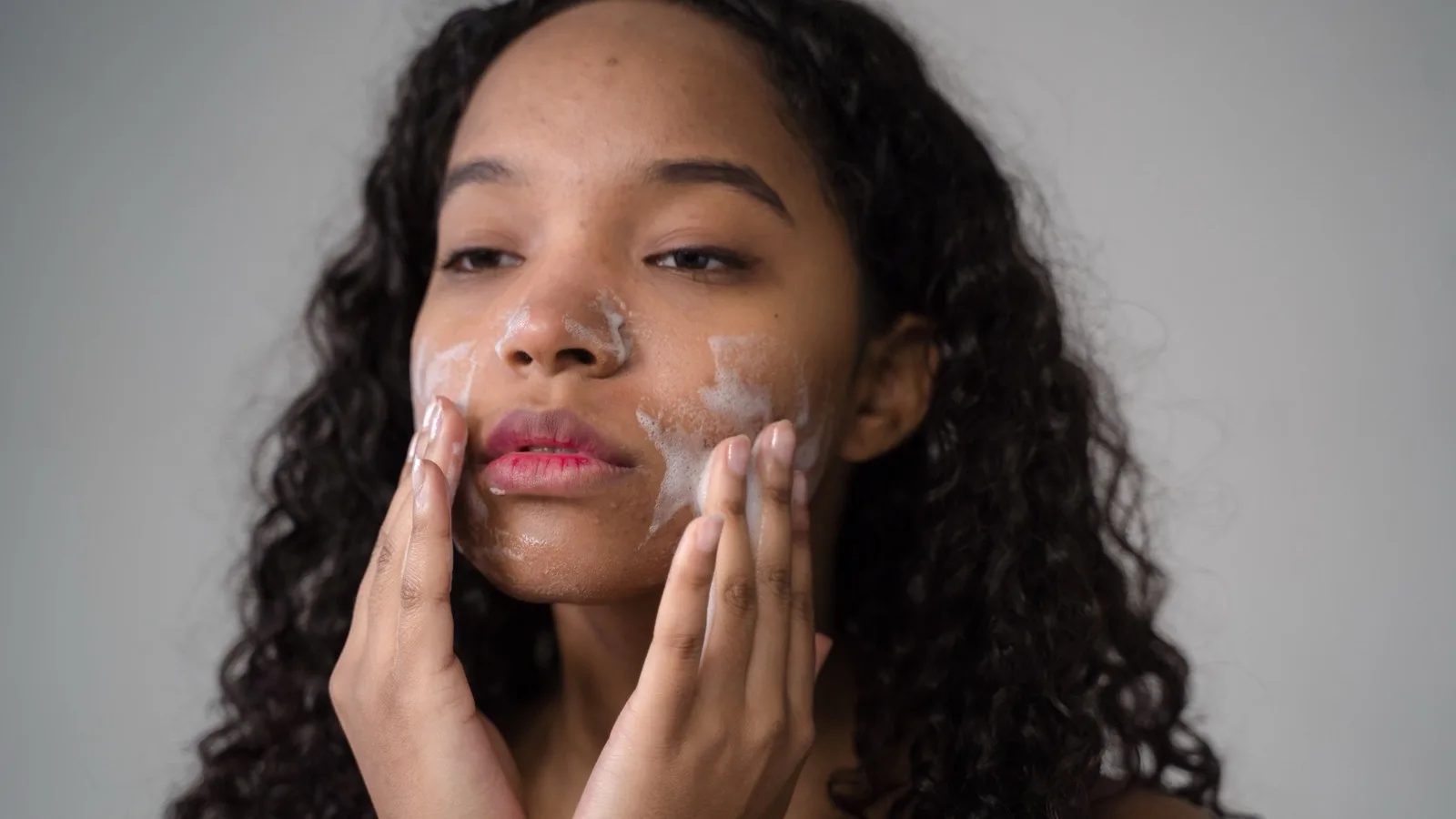 A woman washing her face as part of a gentle skincare routine.