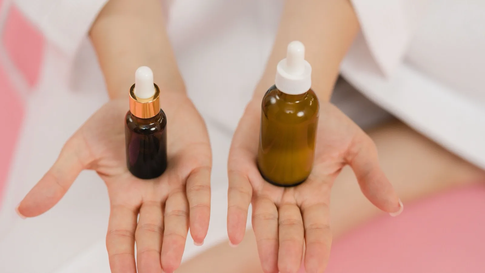 Hands holding cosmetic dropper bottles for skincare comparison.