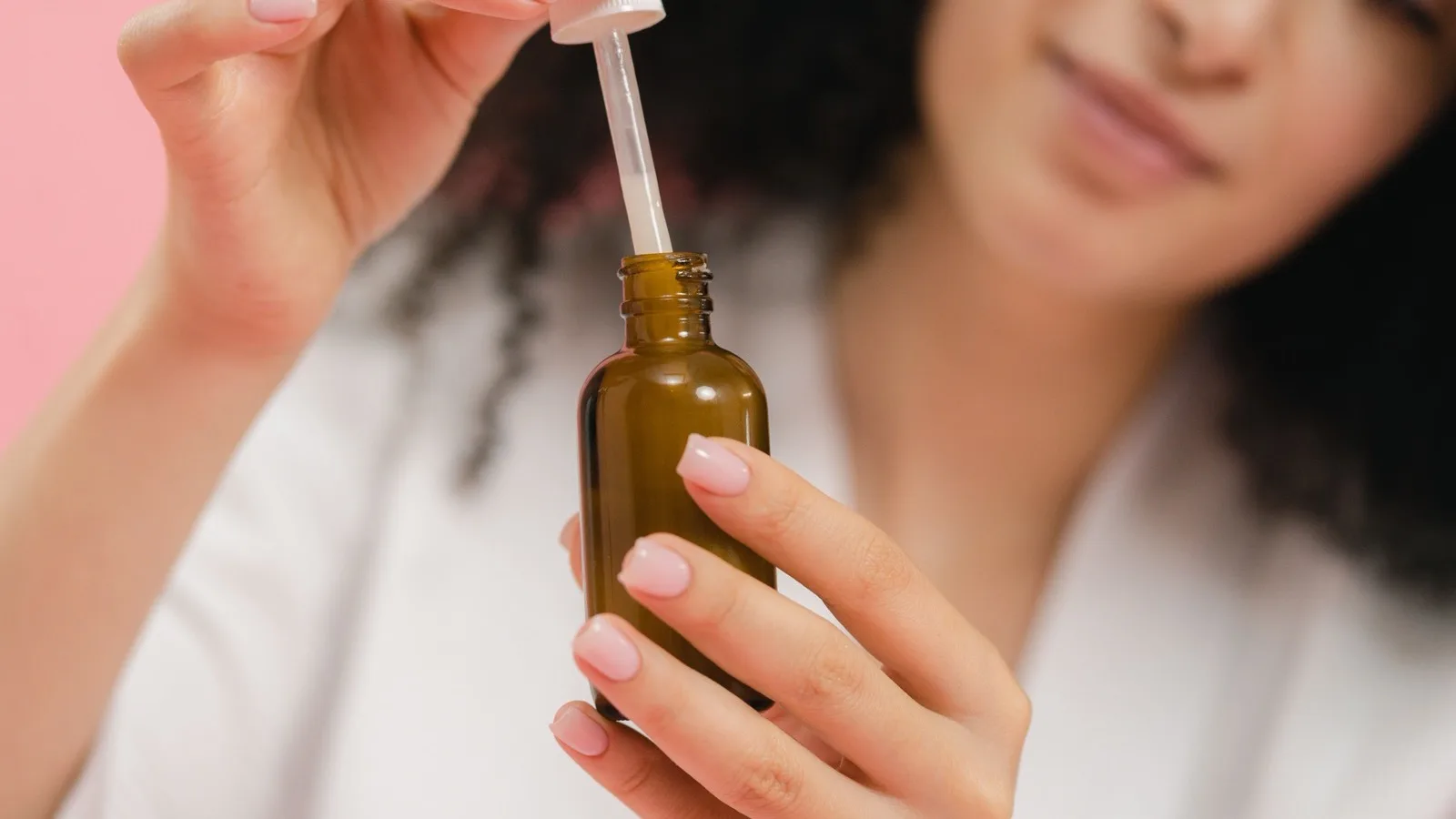 A person holding a dropper bottle as part of a skincare routine.